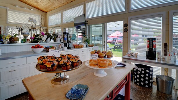 Une cuisine dotée d’un plafond en bois, de grandes fenêtres et d’un comptoir où sont exposées diverses pâtisseries.