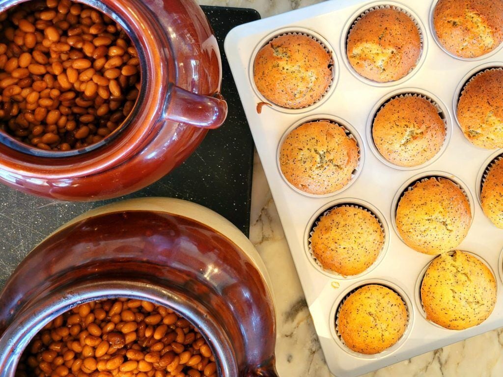 A kitchen with a pot of beans and a muffin tray with baked muffins.
