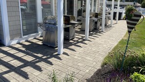 Un espace extérieur abrité, doté de plusieurs barbecues et d’une pergola blanche.