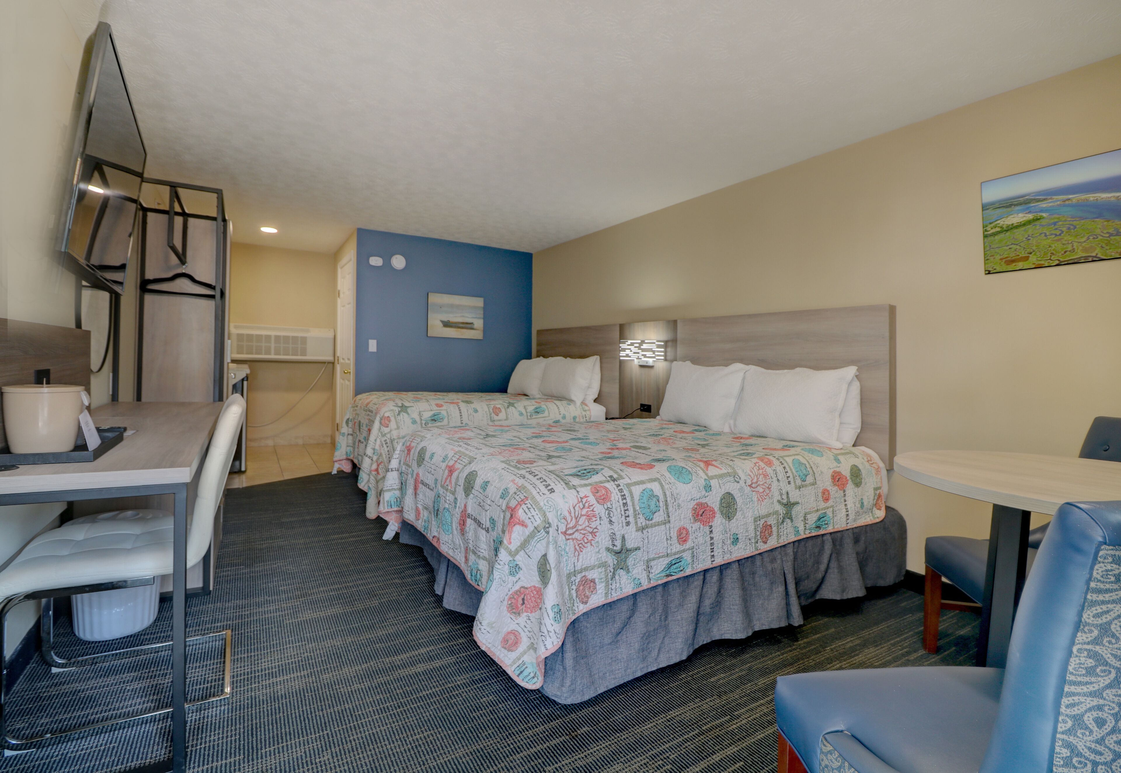 A hotel room with two beds, a desk, and a chair.