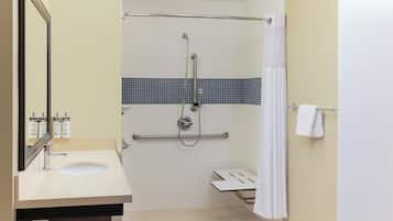 A bathroom with a sink, mirror, shower, and towel rack.