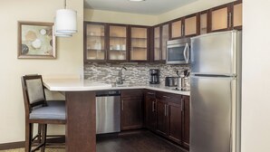 A modern kitchen with dark wood cabinets, stainless steel appliances, and a white countertop.
