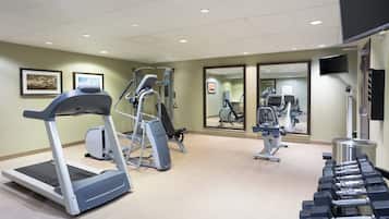 A gym with treadmills, weight machines, and dumbbells.