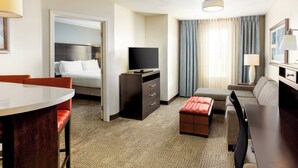 A hotel room with a bed, a desk, a chair, a television, and a sofa.