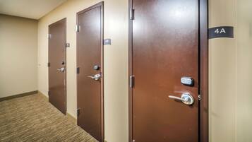 A row of brown doors with numbered signs, carpeted floor, and a plain wall.