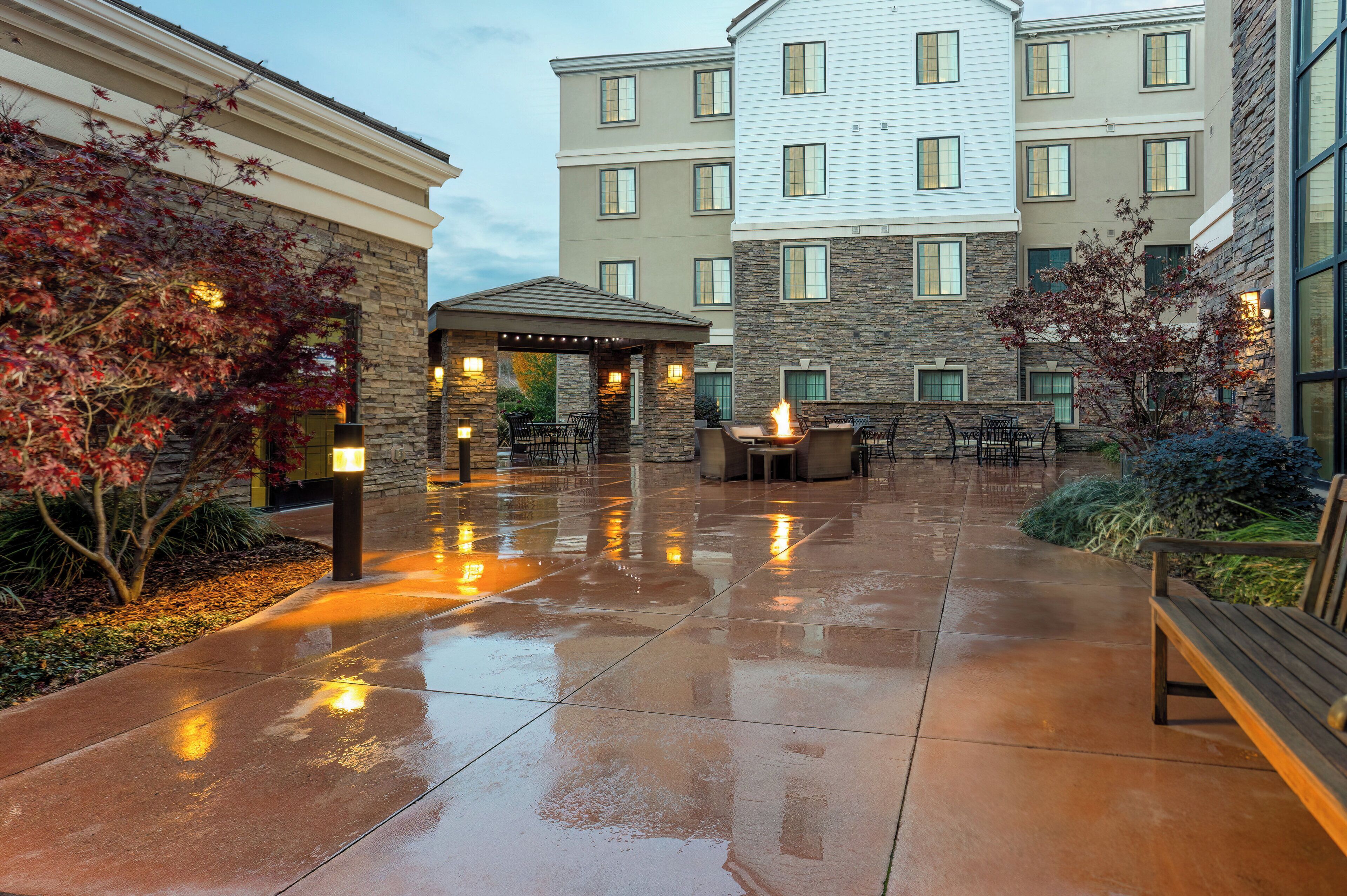 Un patio de hotel con zona de estar techada, muros de piedra y una chimenea.