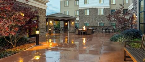 Un patio de hotel con zona de estar techada, muros de piedra y una chimenea.