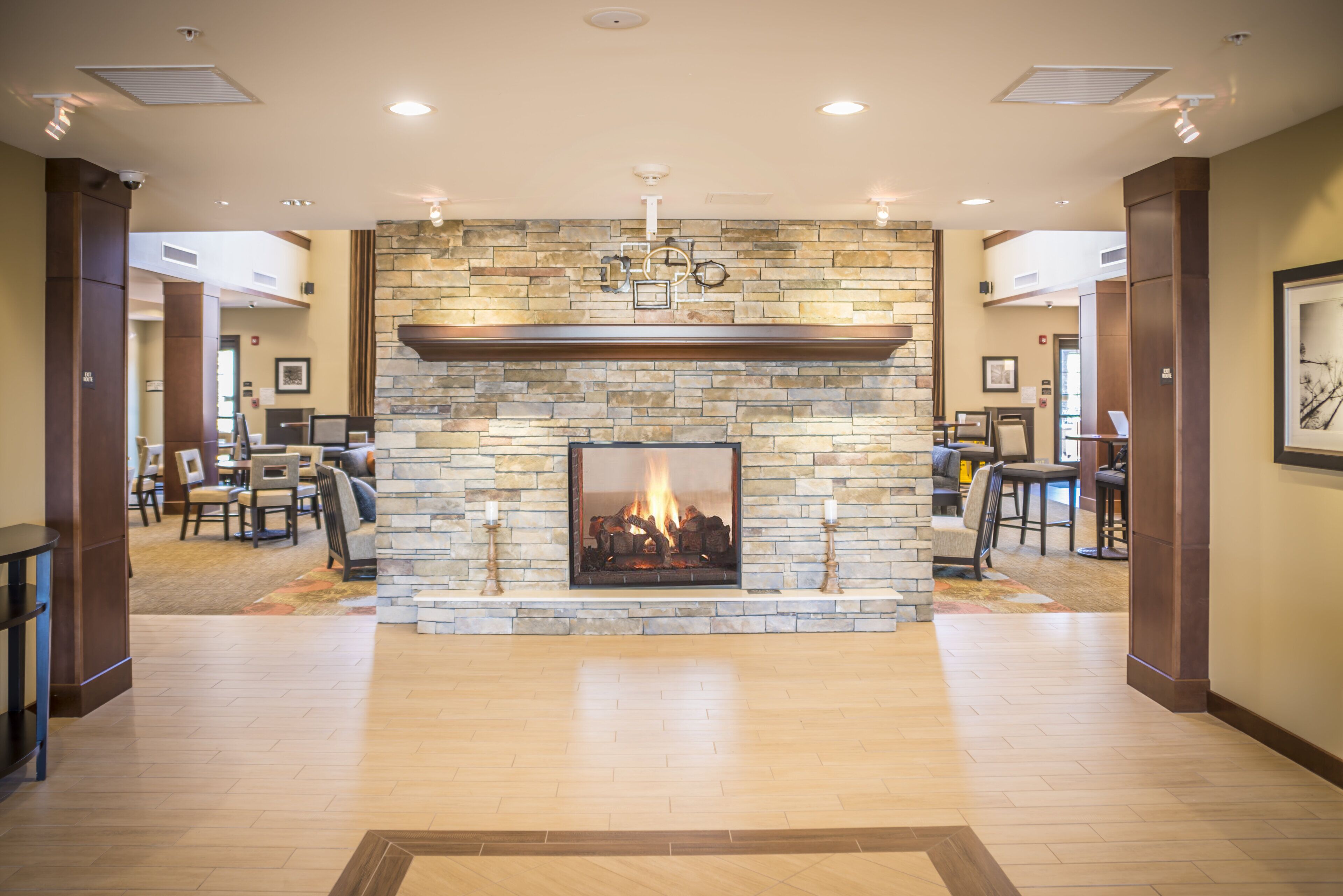 A spacious lobby with a stone fireplace, wooden flooring, and a dining area with tables and chairs.