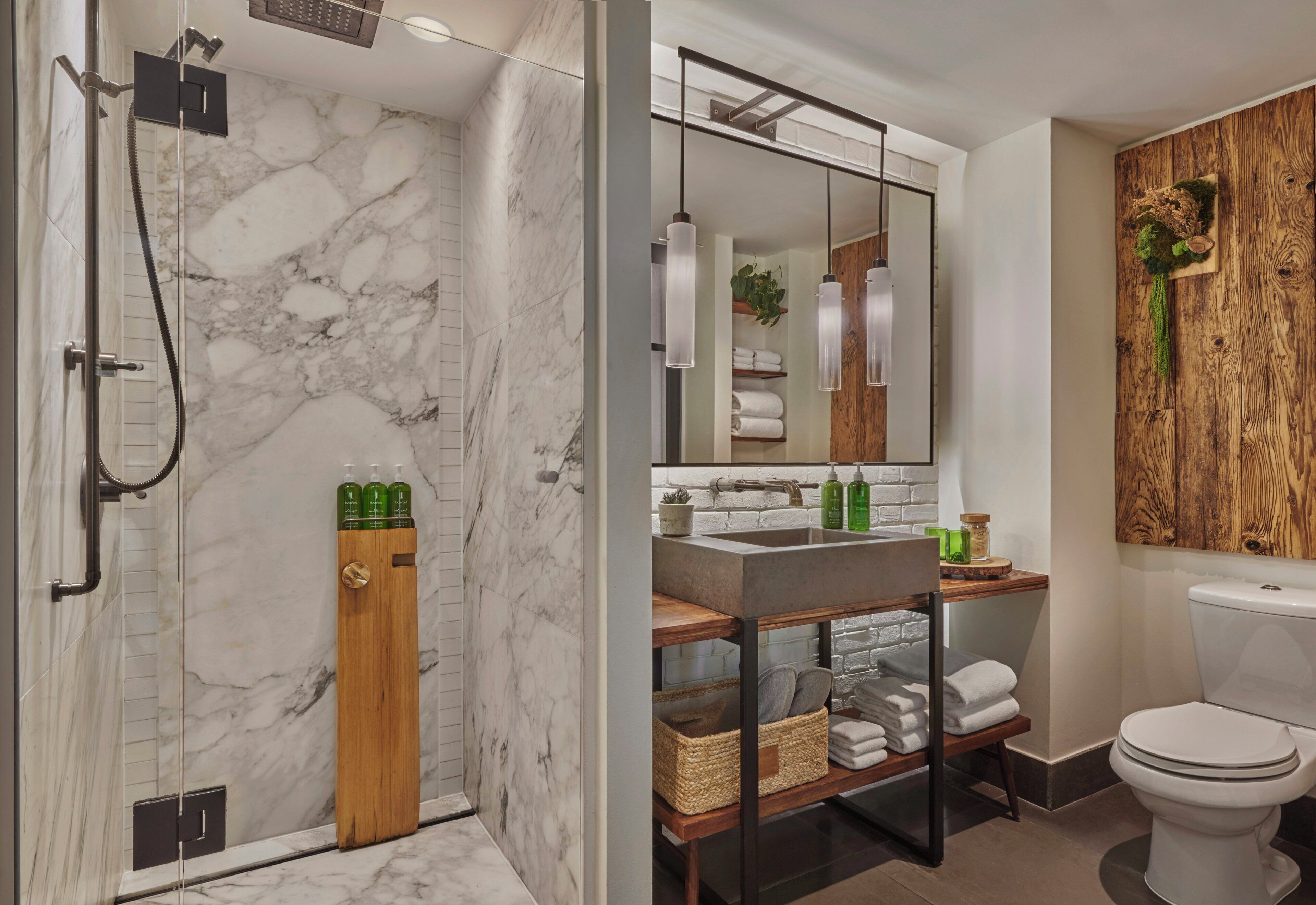 A modern bathroom with a shower, marble walls, a wooden vanity, and a large mirror.