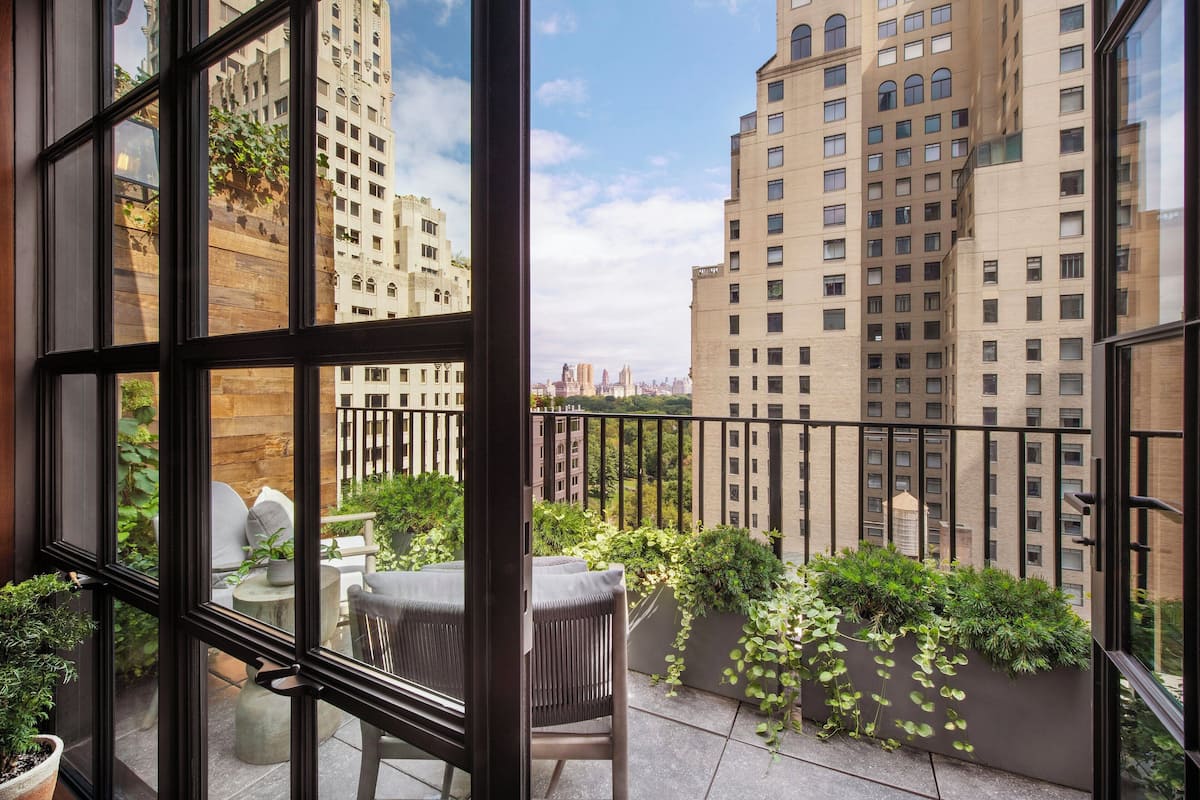 Varanda com vista para edifícios altos, uma planta em vaso e uma cadeira.
