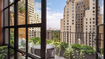 Ein Balkon mit Blick auf hohe Gebäude, einer Topfpflanze und einem Stuhl.