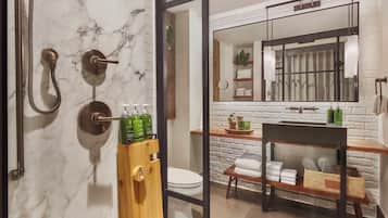 A bathroom with a marble wall, a wooden towel rack, a sink with a mirror above it, and a toilet.