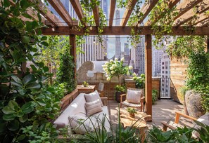 A rooftop garden with a wooden pergola, seating area, and potted plants. - 1 Hotel Central Park (New York)