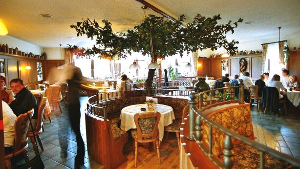 Een restaurant met een centrale zithoek, een trap en uitzicht op de straat.