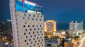 Un hotel moderno de gran altura, con numerosas plantas, un destacado frente de vidrio y vistas a la ciudad y al agua.