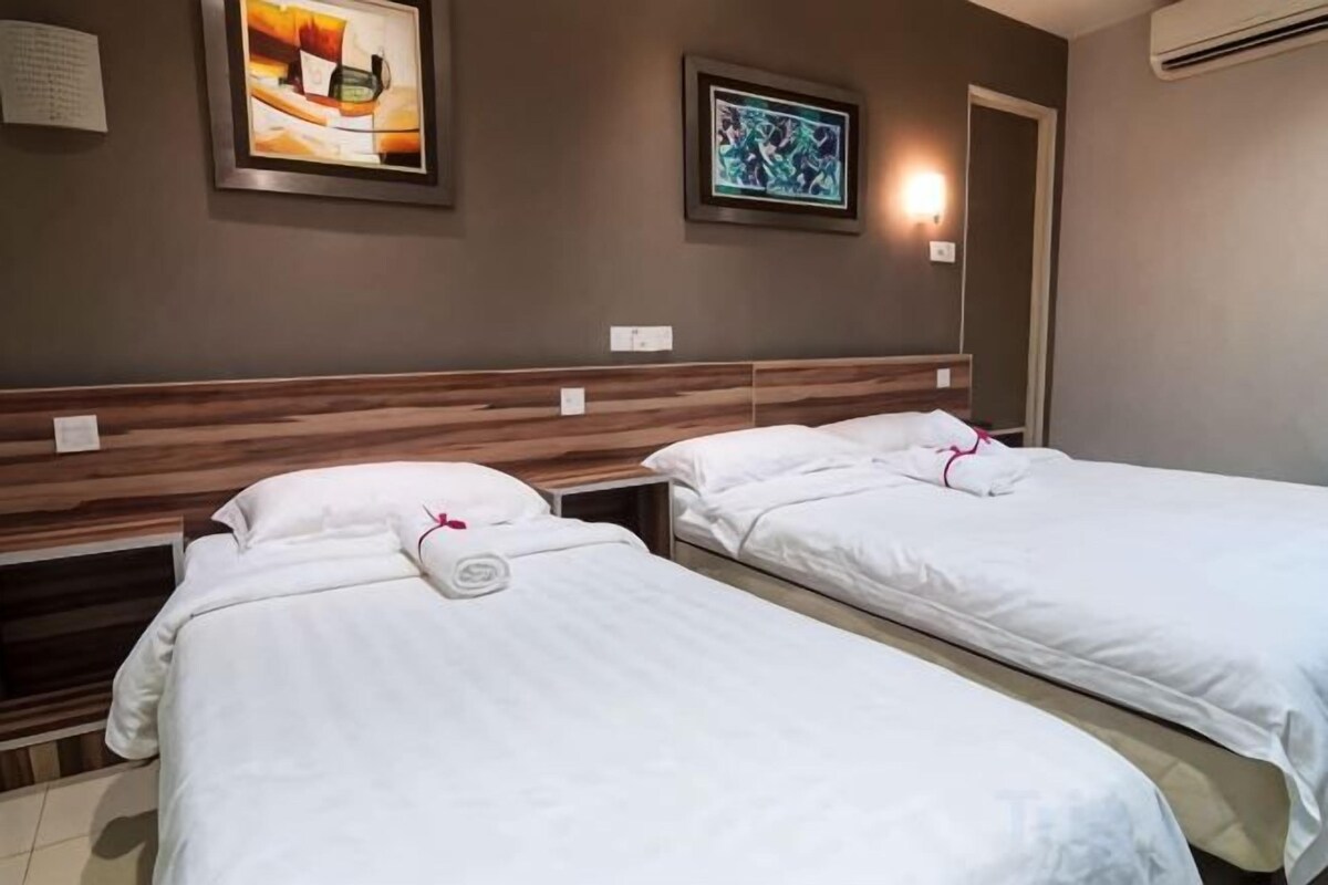 A hotel room with two beds, a wooden headboard, and a framed picture on the wall.