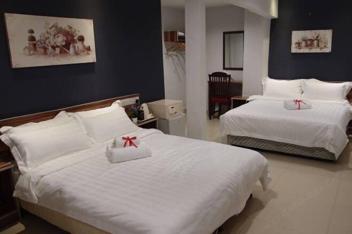 A hotel room with two beds, a nightstand, a chair, and artwork on the walls.