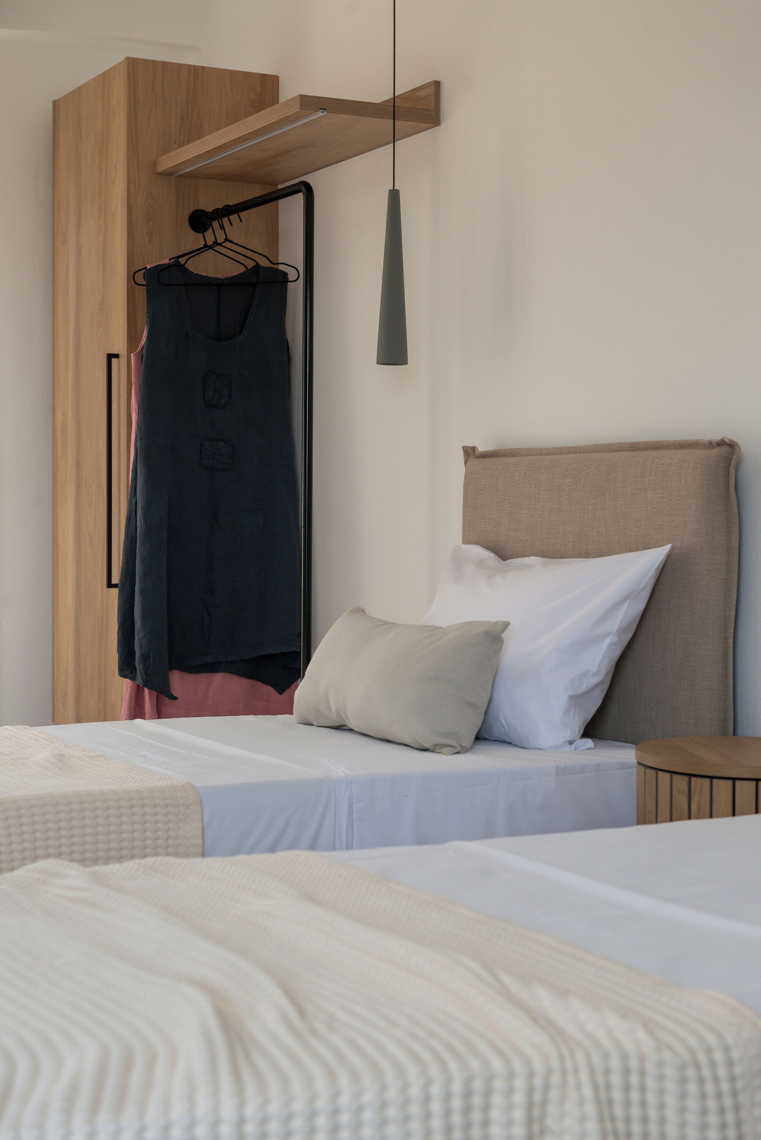 Ein Schlafzimmer mit zwei Betten, einem Holzschrank, einer Hängeleuchte und einem Nachttisch.