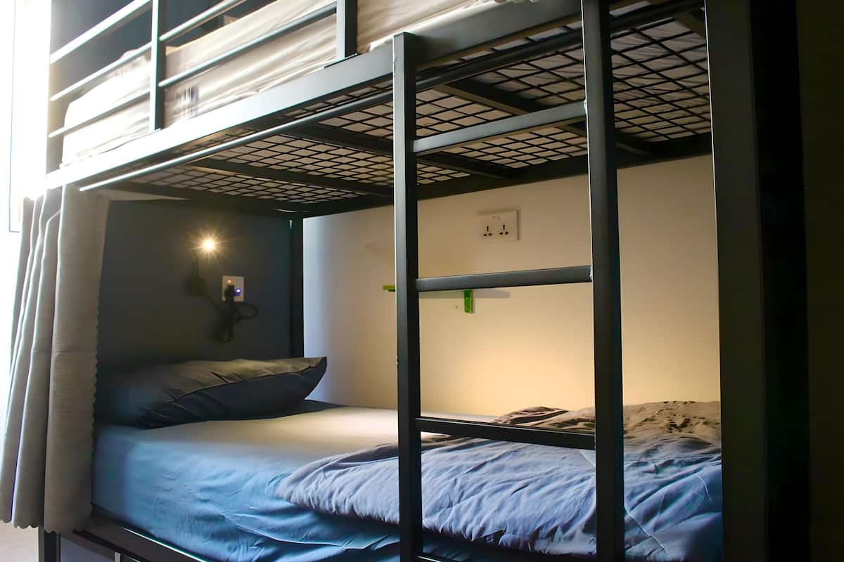 Dormitorio con literas, un enchufe en la pared y una ventana con cortinas.