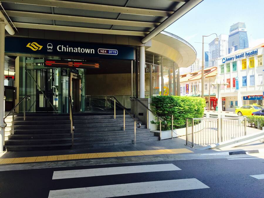 Una escalera que lleva a un edificio con un cartel que dice 'Chinatown MRT NE4 DT19'.