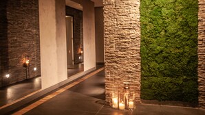 A corridor with stone walls, a moss wall, and candles on the floor. - Rezydencja Nosalowy Dwór (Zakopane)