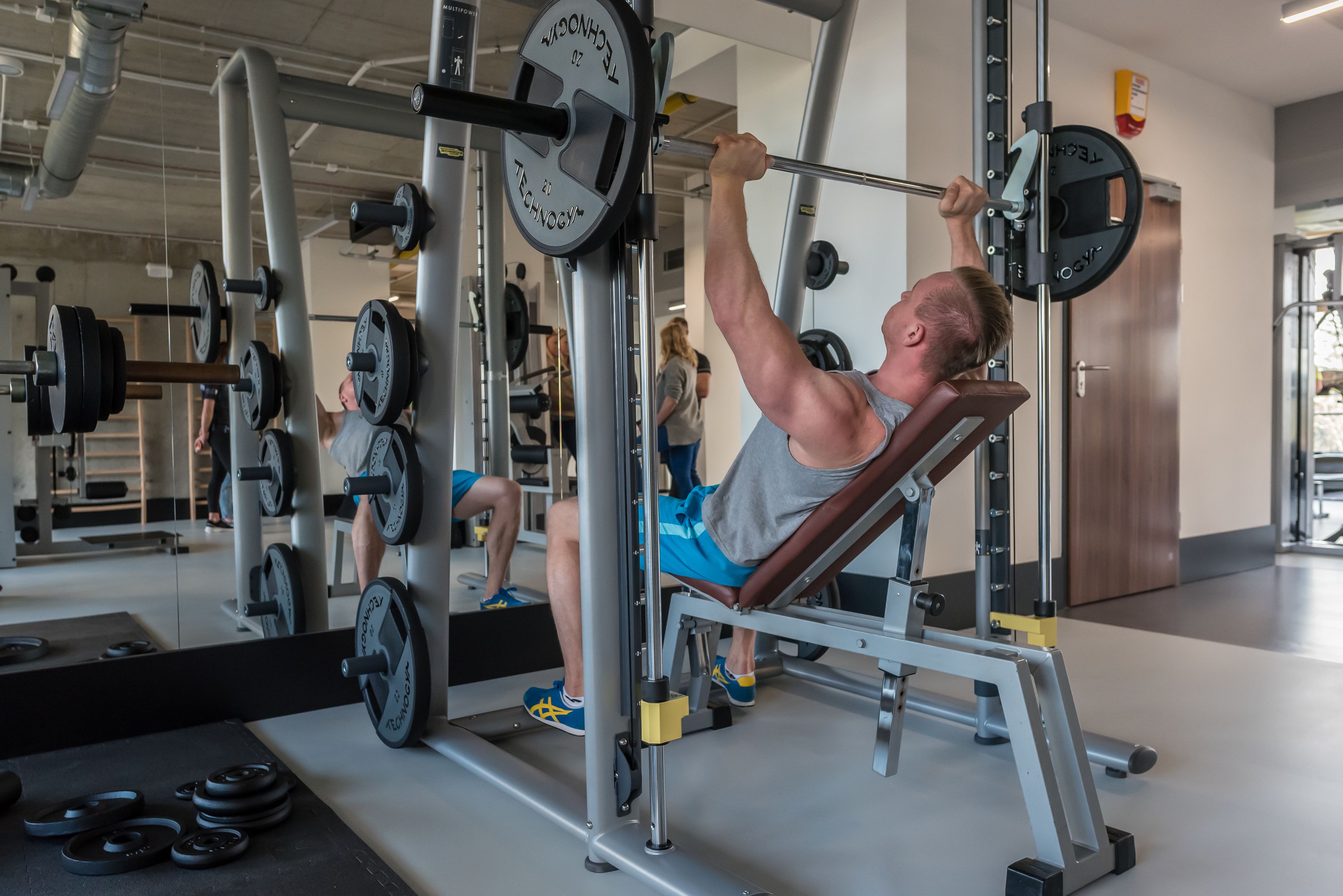 Un gimnasio con equipo de levantamiento de pesas, que incluye una prensa de banca y una estructura para sentadillas.