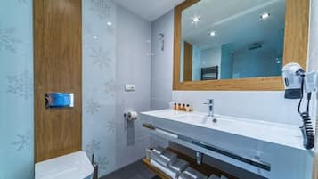 Un baño moderno con tocador de madera, un espejo grande y un perchero para toallas.