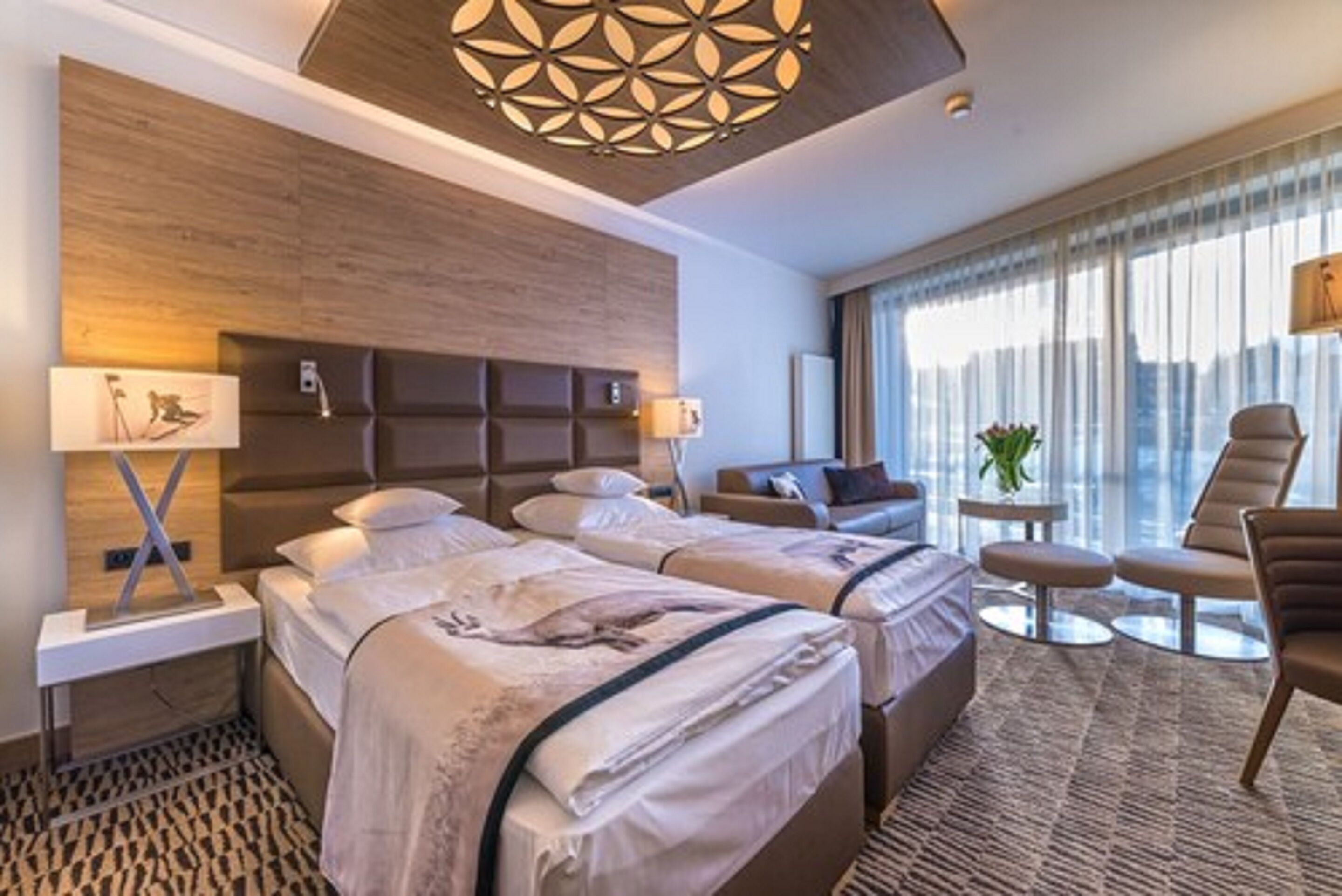 A hotel room with two beds, a sofa, a small table, and a chair.