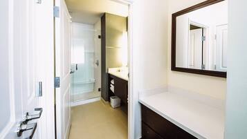 A modern bathroom with a white vanity, a large mirror, and a glass shower enclosure.