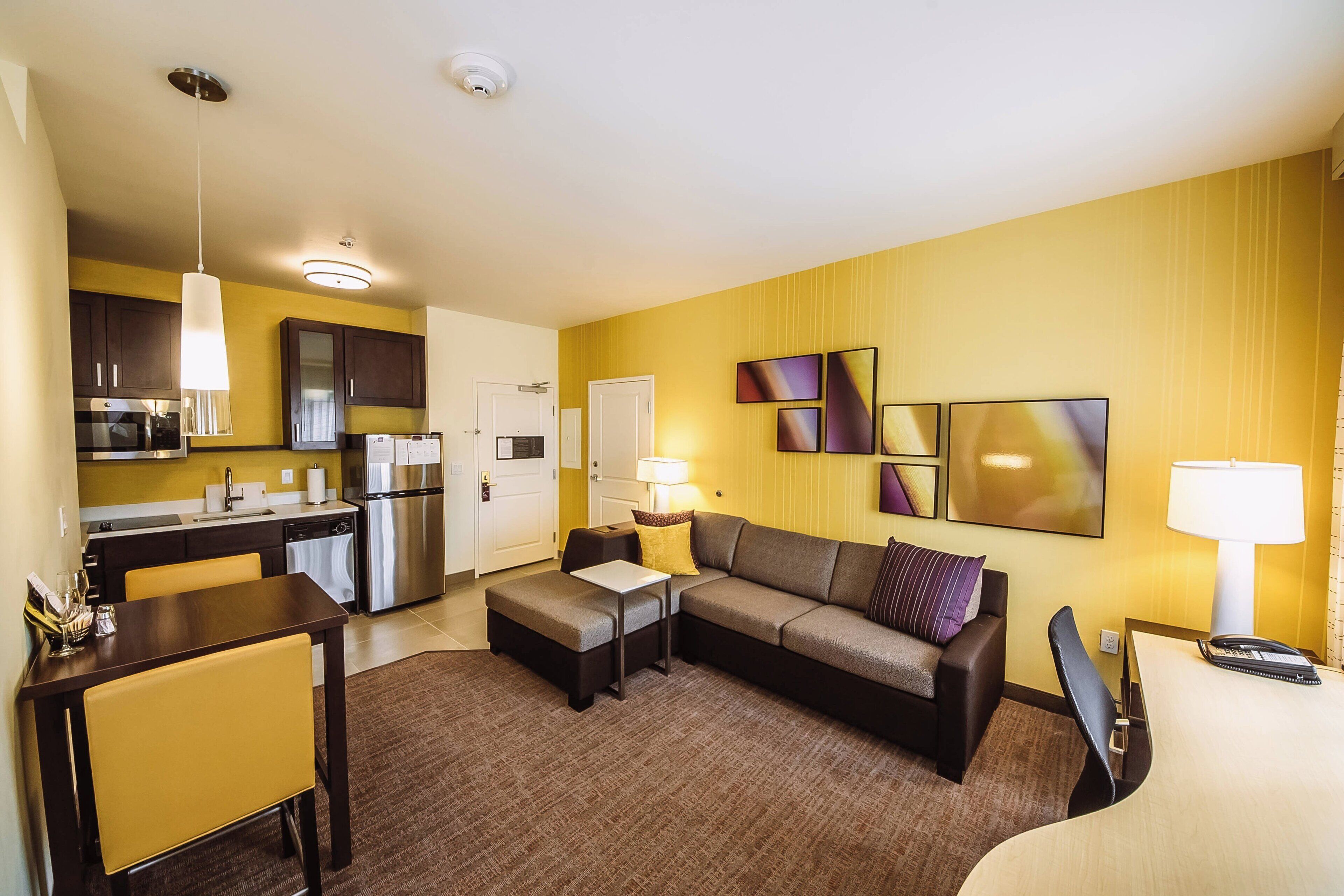 Ein modernes Hotelzimmer mit Küche, Essbereich und Wohnbereich.