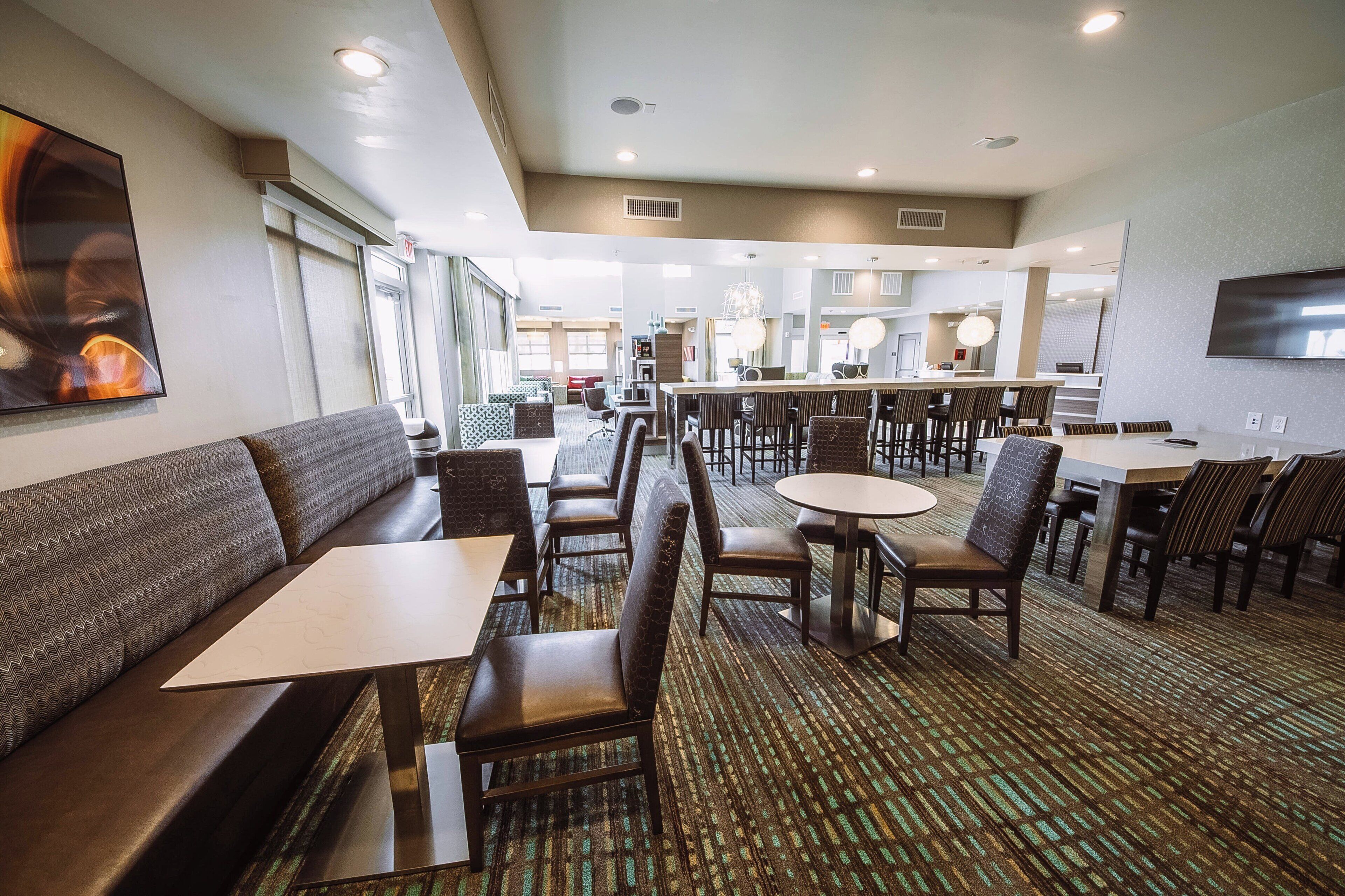A hotel lobby with seating areas, a bar, and a television.