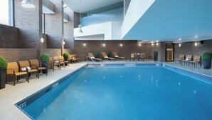Piscina interior con sillones de descanso y pared de ladrillo.