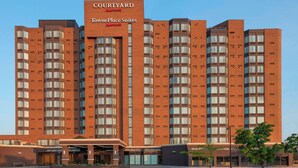 Un hotel TownePlace Suites con patio, fachada de ladrillo, varios pisos y cielo despejado.