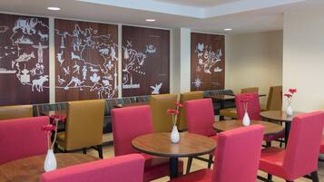 A restaurant with red and brown chairs, round tables, and decorative wall panels.