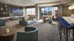Una habitación de hotel moderna con sala de estar, bar y zona de estar con vistas.