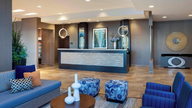 Un vestíbulo moderno con mostrador de recepción, zona de estar y elementos decorativos.