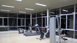 A gym with cardio machines, weight training equipment, and large windows. - Lumpini Ville Naklua Good Luck (Pattaya)