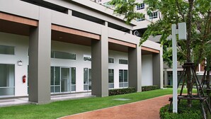A modern building with a covered walkway, large windows, and a fire extinguisher on the wall. - Lumpini Ville Naklua Good Luck (Pattaya)
