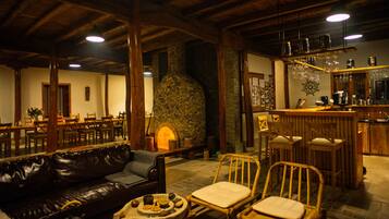 A cozy interior with a stone fireplace, wooden furniture, and a bar area.