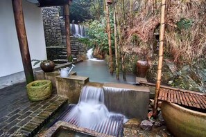 A serene indoor garden with a small waterfall, stone steps, and bamboo structures. - Moganshan Solvang Village Boutique Hotel (Huzhou)