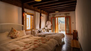 Un dormitorio con dos camas, vigas de madera, una lámpara colgante y vistas por una puerta.