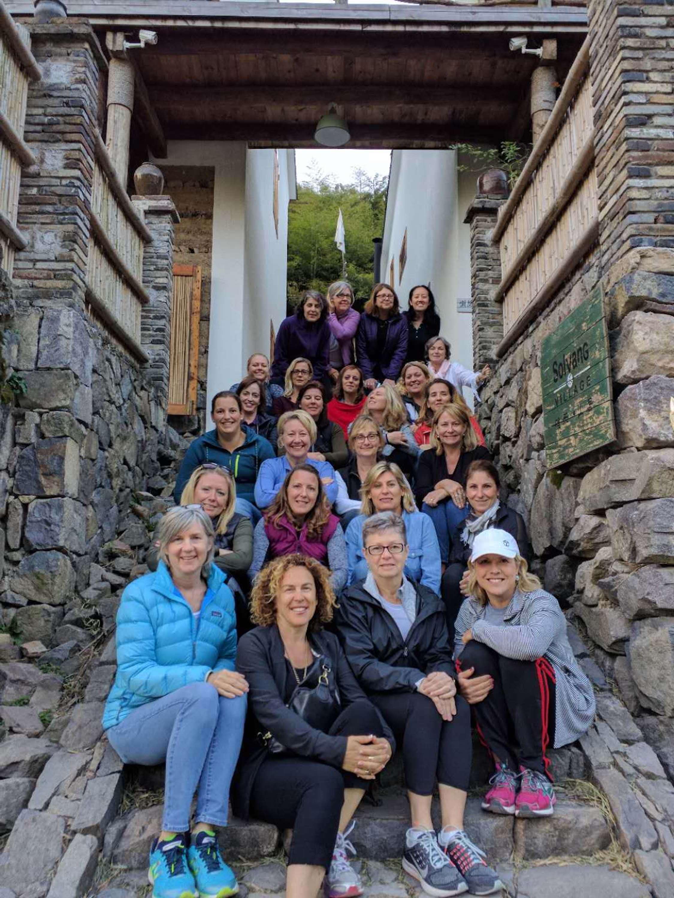 Un grupo de personas sentadas en escalones de piedra dentro de un edificio de piedra con un letrero que dice "Solvang Village".