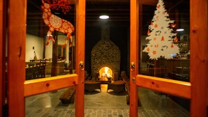 Un interior acogedor con chimenea de piedra, mobiliario de madera y decoraciones festivas.