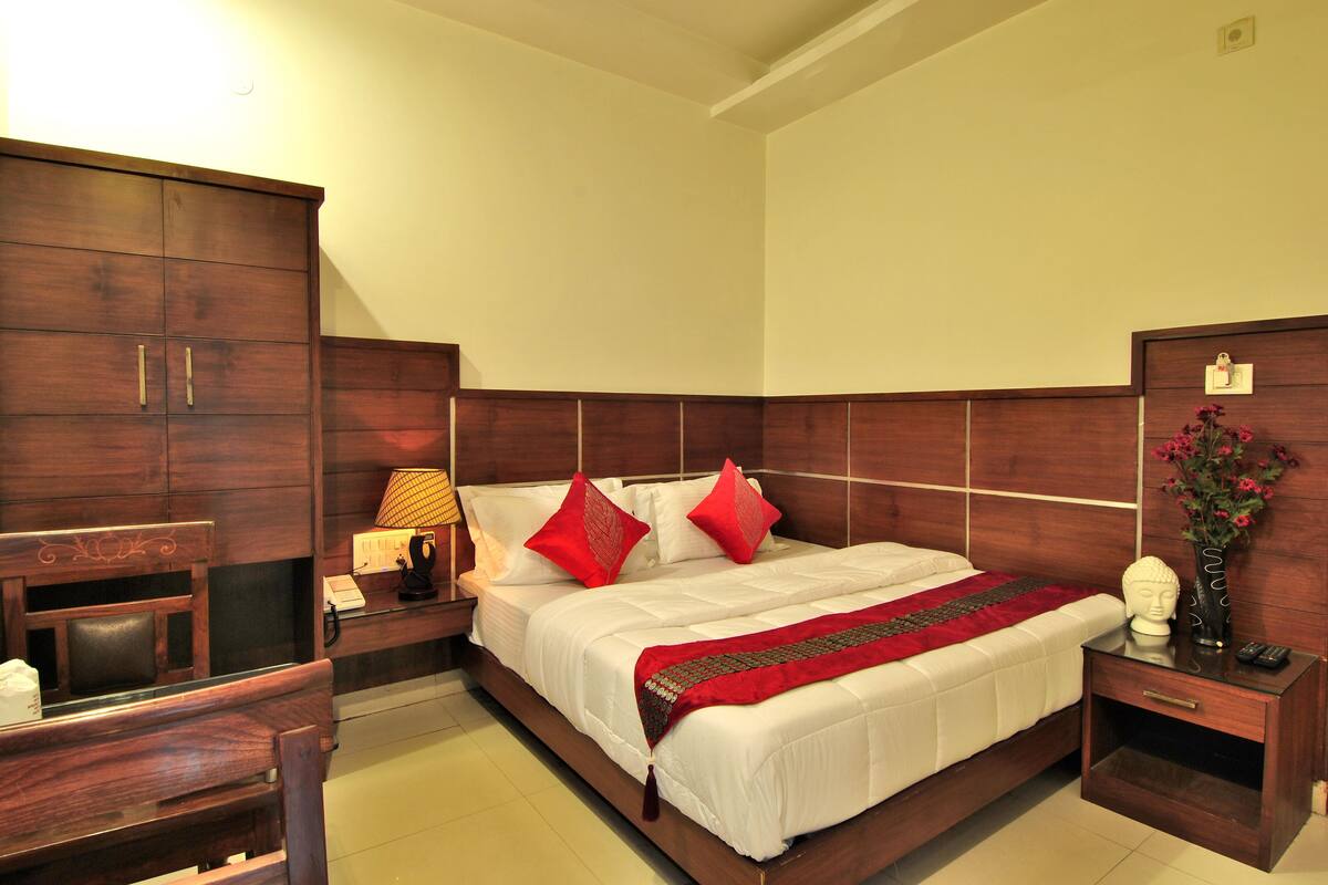 A bedroom with a large bed, wooden headboard, bedside tables, a desk, and a chair.