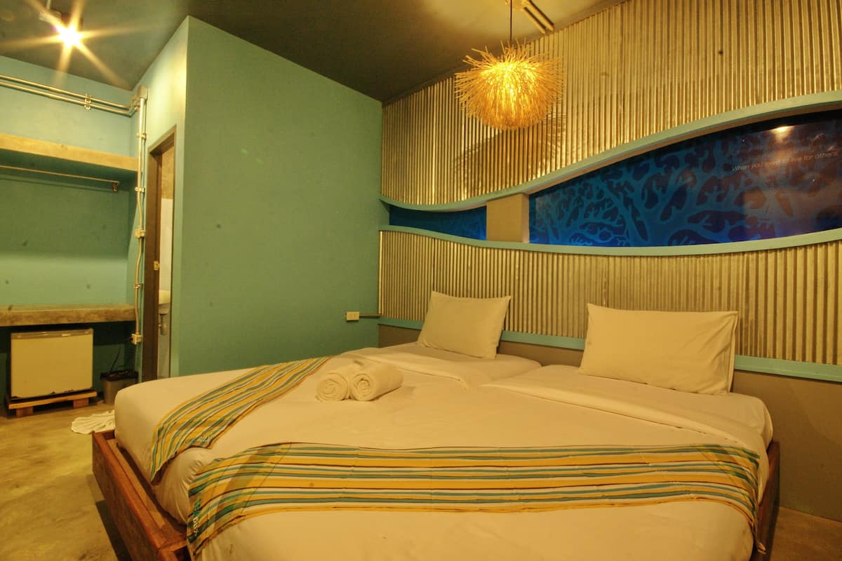 A hotel room with a bed, a desk, and a wall-mounted light fixture.