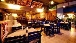 A restaurant interior with tables and chairs, a counter, and hanging menu boards. - Seabox Khaolak Hostel (Takua Pa)
