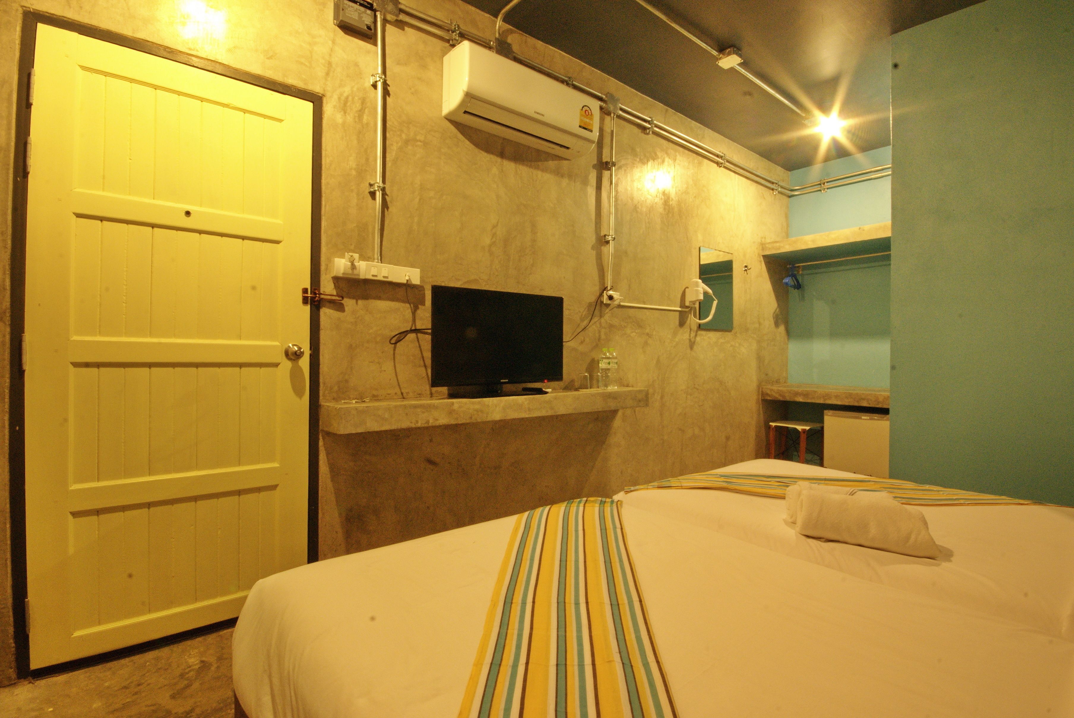 Une chambre d’hôtel équipée d’un lit, d’une télévision, d’un climatiseur et d’une porte.