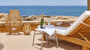 A beachside lounge with a table set for two, a bottle of champagne, and a tray of snacks. - Universal Hotel Cabo Blanco - Adults Only (Ses Salines)