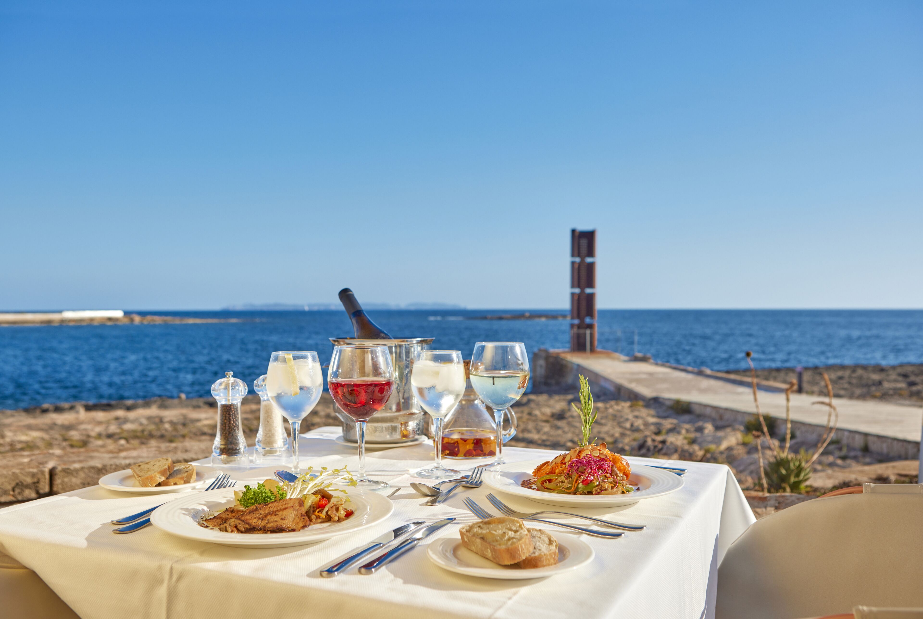 A table set for a meal with a view of the sea.