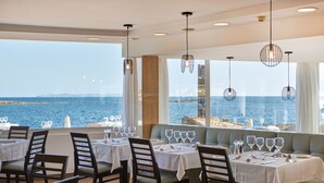 A restaurant with tables set for dining, a view of the sea, and hanging pendant lights. - Universal Hotel Cabo Blanco - Adults Only (Ses Salines)